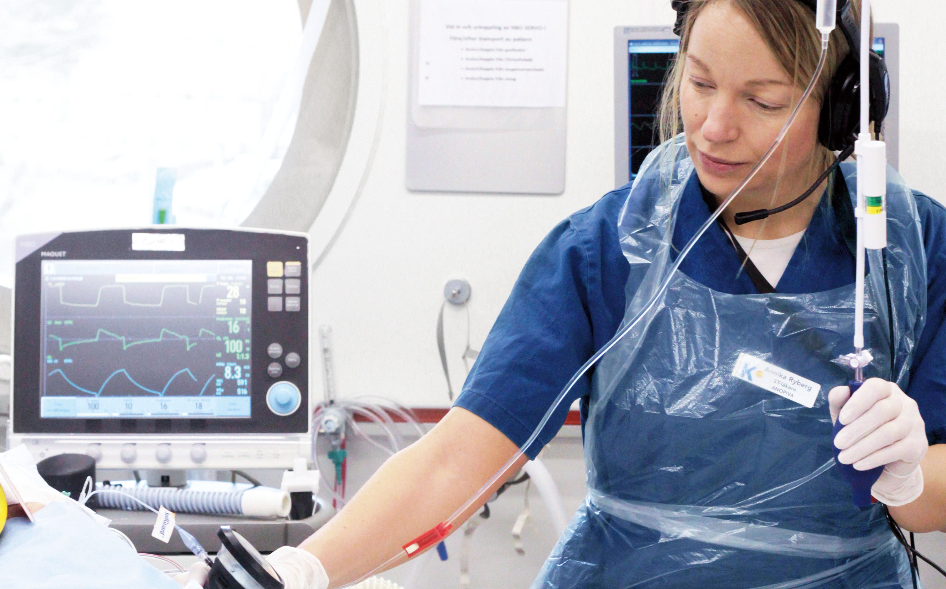 A medical professional in protective gear operates equipment in a hospital setting.