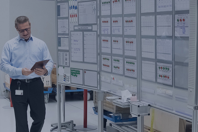 A group of people in an office hallway looking at a wall covered with charts and graphs.
