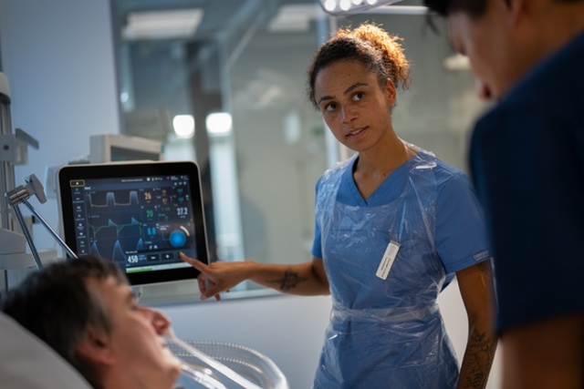 A nurse assists a patient in a hospital room, showcasing care and support in a medical environment.