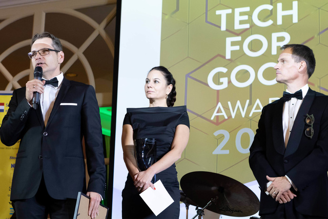 Drie mensen in galakleding staan op het podium tijdens de uitreiking van de Tech for Good Award in 2023.