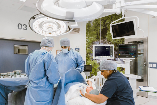 Chirurgen in operatiekleding voeren operatie uit in een moderne operatiekamer met medische apparatuur.
