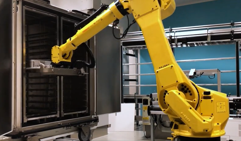 Un bras robotisé fonctionne sur une machine dans une usine, présentant une technologie d'automatisation avancée avec T-DOC.