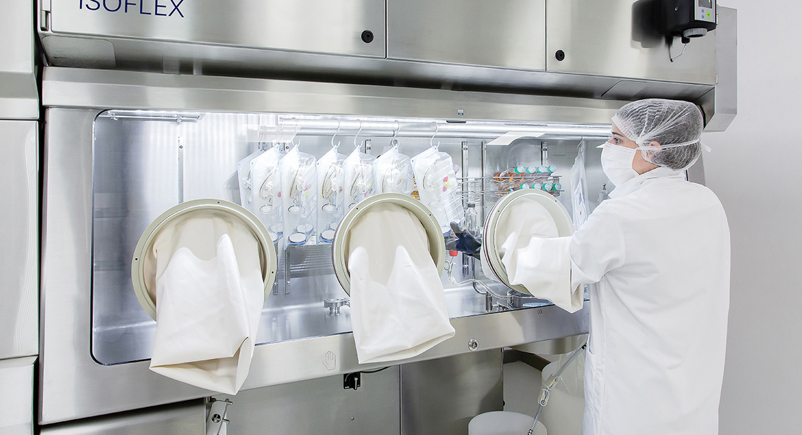 Laboratoy operator wearing mask  removing sterile goods from  ww5 Isoflex isolator 