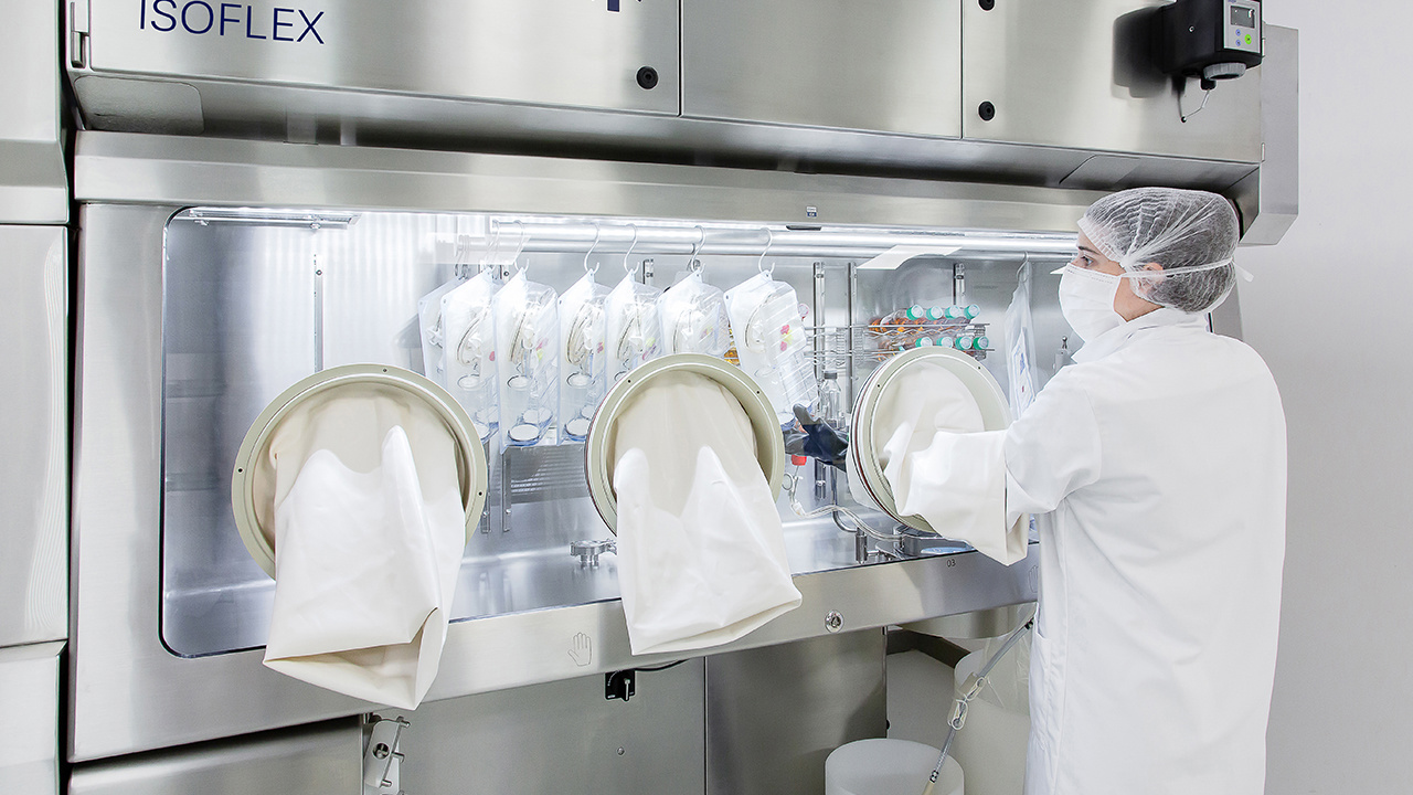 Laboratoy operator wearing mask  removing sterile goods from  ww5 Isoflex isolator 