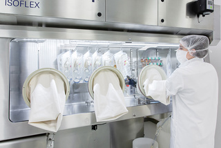 Laboratoy operator wearing mask  removing sterile goods from  ww5 Isoflex isolator 