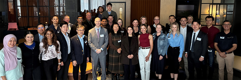 Large group of conference attendees standing together indoors at the APAC EVH Summit in Sydney, Australia. The group is arranged in several rows, facing the camera, wearing business and smart-casual attire with name badges. 