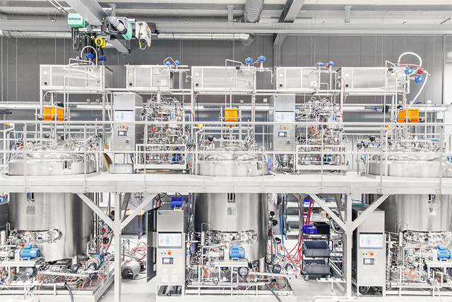 A high-tech pharmaceutical manufacturing facility with large stainless steel tanks and intricate piping systems.