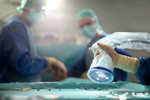 Surgical team in a bright operating room, with tools on a table and a gloved hand adjusting a surgical light.