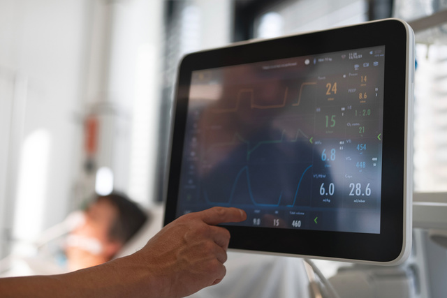 Close up of screen with high-acuity patient behind  