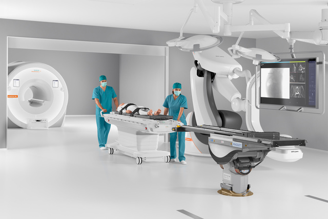 Medical staff prepare a patient in a modern surgical room with advanced imaging equipment.