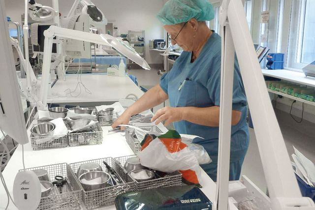 Person in scrubs organizing medical instruments in a sterile hospital environment.